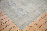 Bottom left corner of a vintage Oushak carpet with faded beige and slate blue motifs.