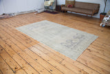 Vintage Oushak carpet with soft beige, grey, slate blue airy patterns, angled view.