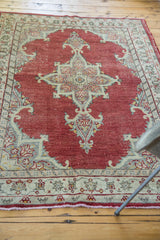 Vintage Oushak rug close-up showing cherry red field and intricate ivory and slate grey border.
