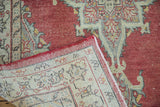 Vintage Oushak rug folded to reveal ivory foundation and finely hand-knotted patterns.