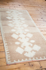 Angled view of vintage Oushak runner's minimalist tone-on-tone geometric pattern.