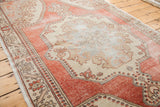 Distressed Oushak rug pile, softened cranberry red field and powder blue medallion.
