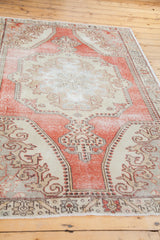 Distressed pile and intricate ivory patterns on a cranberry red vintage Oushak rug.