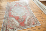 Distressed Oushak rug in faded cranberry red, featuring a muted blue medallion and ivory details.