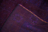 Folded corner of vintage Overdyed Oushak rug, showing deep royal blue violet pile and woven back.