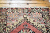 Fringed corner of a vintage Oushak rug, showing geometric borders in lavender, brick red, and cream.