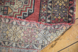Folded vintage Oushak rug displaying hand-knotted weave and brick red geometric motifs.