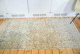 Distressed texture and faded allover patterns on a sea foam green Sivas rug corner.