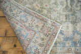 Distressed vintage Sivas rug rolled back, revealing abrashed sea foam green pile and woven foundation.