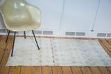 Distressed modern Oushak rug with a blanched lattice motif and soft pastel hues.
