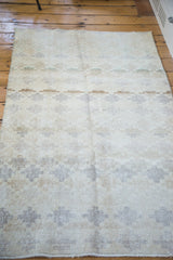 Sun-faded, distressed texture revealing a blanched lattice motif with subtle pastel accents.