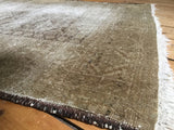 Distressed Belouch rug pile showing faded brown serrated leaf design peeking through.