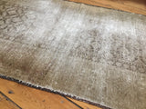 Distressed Belouch rug texture with faded serrated leaf design peeking through.