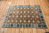 Vintage Oushak rug corner showcasing brown lattice pattern and teal geometric star border.