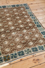 Vintage Oushak rug with brown allover lattice, cream floral motifs, and geometric teal border.