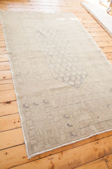 Blanched grey and silver white tones of a distressed Oushak rug's faded central pattern.