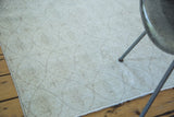 Distressed modern Oushak rug surface with light beige tone and faint oblong lattice.