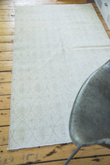 Distressed modern Oushak rug in light beige with subtle oblong lattice lozenges.