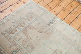 Corner of vintage Turkish Oushak rug, sandy beige field and geometric border.