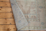 Vintage Oushak rug corner with tightly woven back, light fringe, and sandy beige tones.