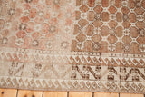 Distressed Oushak carpet with faded rose and warm brown lattice, detailed geometric border.
