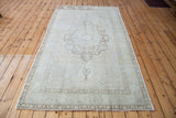 Sun-faded central medallion and lower border on a blanched vintage Turkish Oushak carpet.