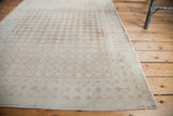 Softened beige and ivory distressed Oushak rug corner with diamond lattice and border.