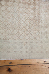 Softened beige border pattern and delicate fringe of the distressed Oushak rug.