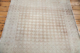 Distressed harlequin diamond pattern in softened beige and antique ivory on Oushak rug.