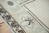 Faded ivory and beige field with distinct charcoal geometric border on vintage Oushak rug.