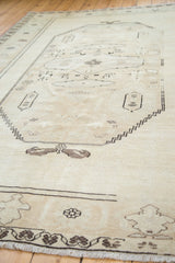 Vintage Oushak rug's faded ivory pile, dark geometric border, and light fringe.