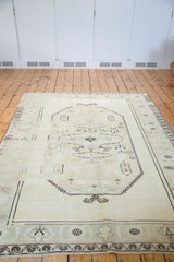 Faded ivory Oushak carpet lower border detail with light green and geometric motifs.