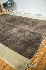 Vintage Moroccan rug's shaggy two-tone wool pile, showing abrash and ivory fringe.