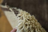 Thick natural wool pile of a vintage Moroccan carpet showing ivory and deeper tones.