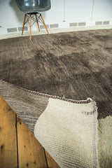 Curled corner of vintage Moroccan carpet, revealing natural ivory woven back and plush silver grey pile.