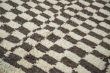 Vintage Moroccan carpet pile featuring a shaggy dark brown and cream checkered motif.