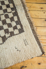 Shaggy off-white Moroccan rug pile with dark brown checkered pattern and woven numbers.