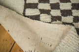 Vintage Moroccan rug corner, revealing thick brown and off-white checkered pile and woven foundation.