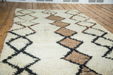 Geometric black and brown diamond lattice on ivory shag pile of this Moroccan rug.
