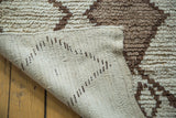 Vintage Moroccan rug's woven ivory back contrasts its textured charcoal and ivory pile.