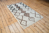 Corner of vintage Moroccan rug revealing textured ivory pile, brown, and charcoal diamonds.