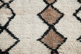 Shaggy pile detail of a vintage Moroccan rug, featuring ivory, brown, and black lattice motif.