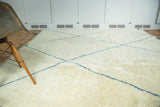 Angled view of shaggy ivory pile, chalk-sky blue geometric lines on a Moroccan carpet.