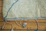 Deep pile, chalk-sky blue line pattern, and braided tassels of a vintage Moroccan carpet.