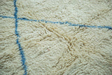 Shaggy pile texture of a vintage Moroccan carpet, showing pale ivory and chalk-sky blue lines.