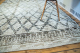 Vintage Moroccan carpet's shaggy ivory pile, charcoal lattice, and running 'T' border.