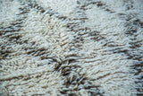 Shaggy wool pile with blanched ivory and charcoal grey pattern on the Moroccan carpet.