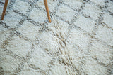 Plush texture of ivory and varying charcoal grey lattice motif on the Moroccan carpet.