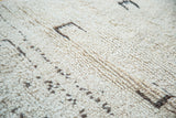 Vintage Moroccan rug's textured wool pile, featuring raised lines and abstract brown motifs.