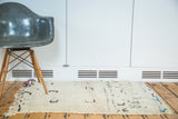 Shaggy off-white vintage Moroccan rug pile with playful abstract motifs and colorful fringe.